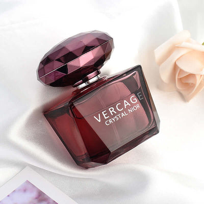 Versage Crystal Noir perfume bottle with a diamond-shaped cap on silky fabric, showcasing its luxurious design.