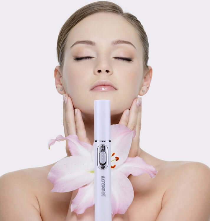Woman using blue light therapy acne laser pen for skincare treatment, holding flower and smiling.