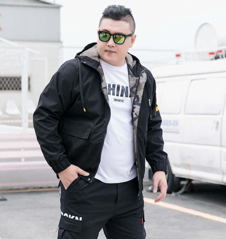 Stylish man wearing a bomber jacket with sunglasses, showcasing modern casual fashion outdoors.