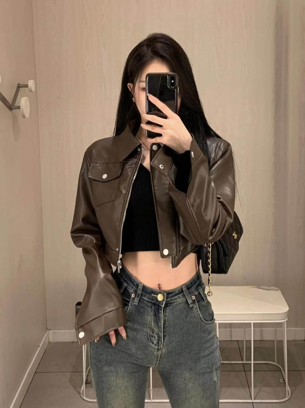 Stylish woman wearing a brown leather motorcycle jacket with flying sleeves, showcasing a trendy urban look.