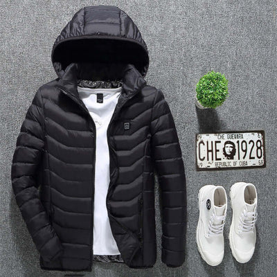 Black heated jacket with hood, layered over a white shirt, paired with white shoes and a small decorative plant.