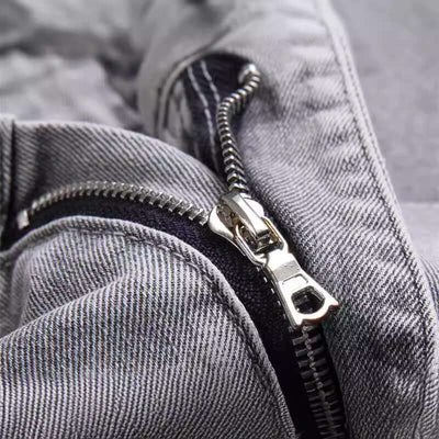 Close-up of the zipper detail on gray snake embroidered men's jeans, showcasing quality craftsmanship and style.
