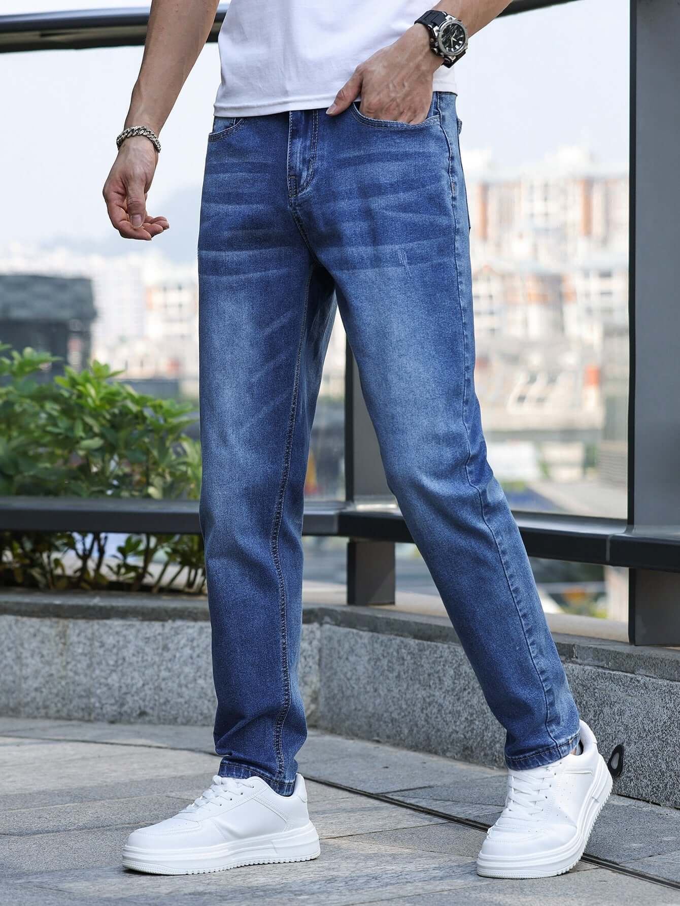 Man wearing light blue stretch slim jeans with a mid waist, paired with white sneakers for a casual look.
