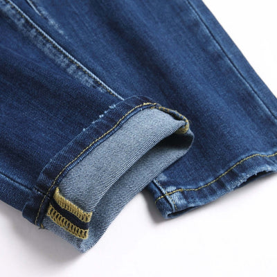 Close-up of the cuff of new blue ripped slim stretch denim trousers, showcasing detailed stitching and fabric texture.