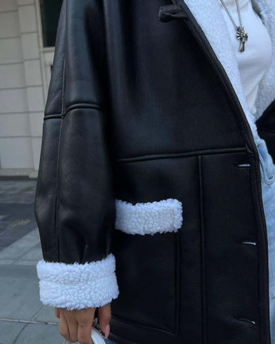 Close-up of a black leather and white fur splicing coat with long sleeves and pockets, perfect for women.