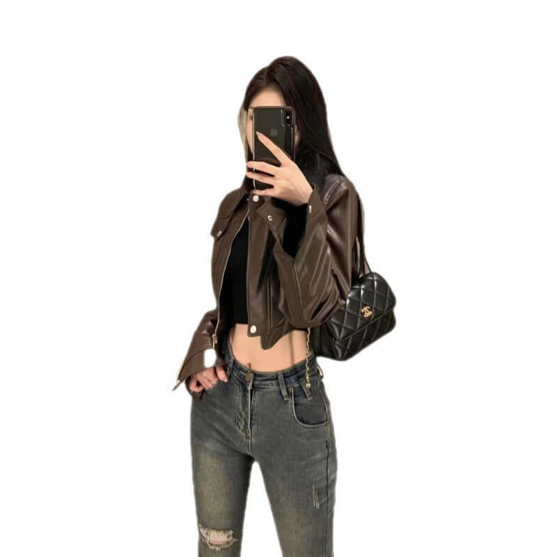 Stylish woman wearing a coffee color leather motorcycle jacket with flying sleeves and jeans.