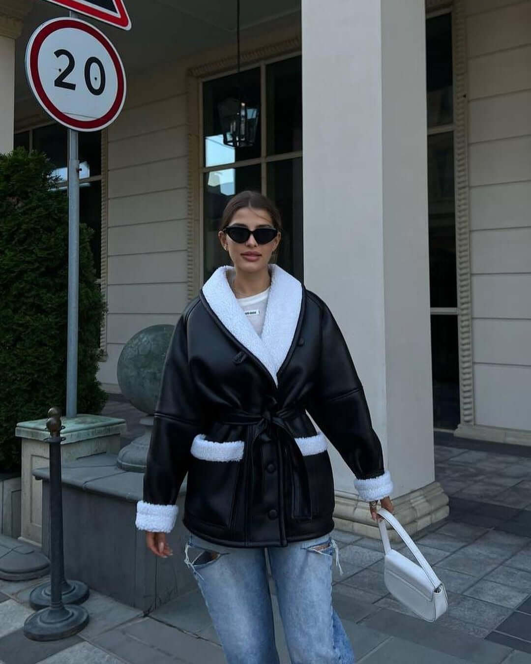 Woman wearing a Korean-style long sleeve splicing coat, combining black imitation leather and white fur, styled with sunglasses.