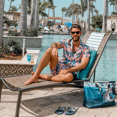 Man relaxing by the pool in stylish tropical shirt and shorts, enjoying summer vibes and sunshine.