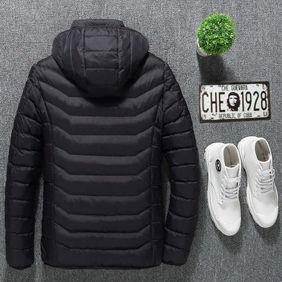 Black heated jacket with removable hood, lightweight design, paired with white sneakers and a small plant.