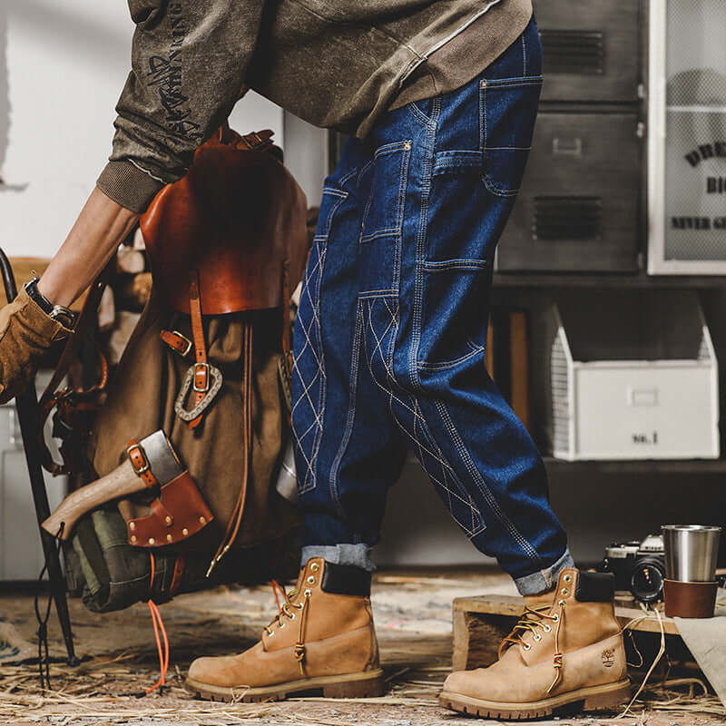 Man wearing blue retro workwear jeans with bright line details, styled for autumn, paired with tan boots in a casual setting.
