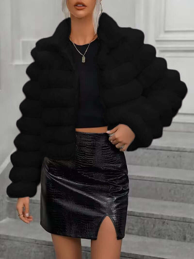 Short black imitation fur coat for women, featuring a faux fur collar, paired with a sleek black skirt.