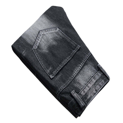 Men's black denim jeans folded showing decorative stitching and a straight leg design.