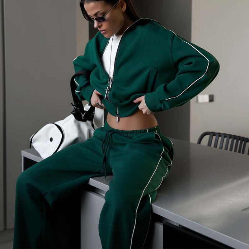 Woman wearing a green sports lace trousers two-piece set with a zipper, styled in a modern indoor setting.