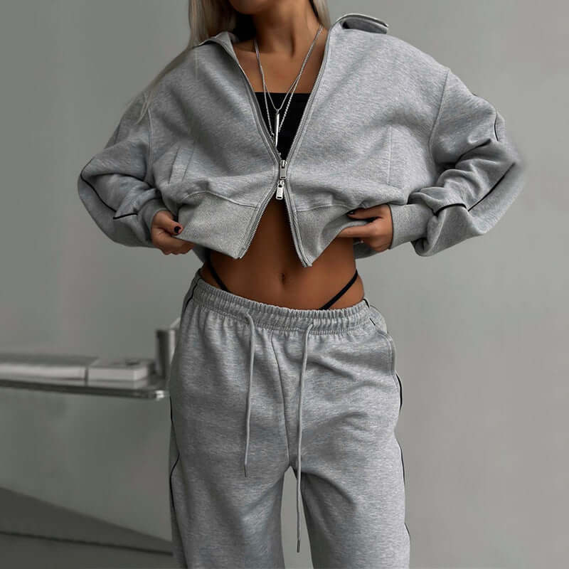 Model wearing gray sports lace trousers two-piece set with long sleeves and zipper detail, showcasing a stylish casual look.