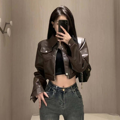 Female model wearing a coffee color leather motorcycle jacket with flared sleeves and jeans.
