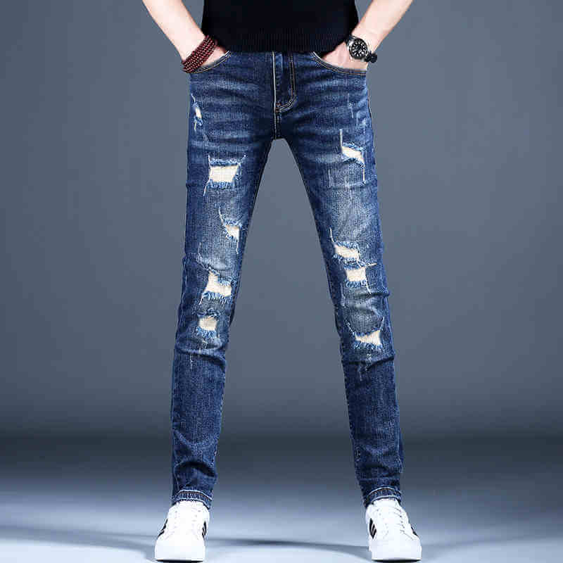 Men's ripped skinny jeans in dark blue denim with distressed detailing, styled casually with white sneakers.
