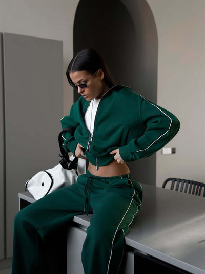 Model wearing green Sports Lace Trousers two-piece set with zipper, styled casually in a modern kitchen.