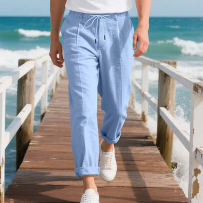 Light blue linen men's casual pants, perfect for summer leisure wear, styled on a beach pier.