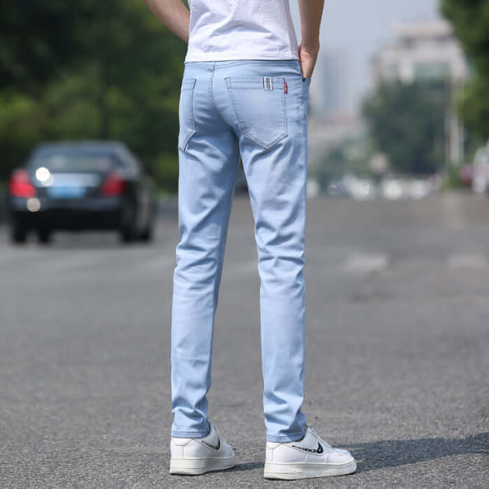 Men's light blue slim straight stretch denim trousers seen from the back, perfect for spring and summer.