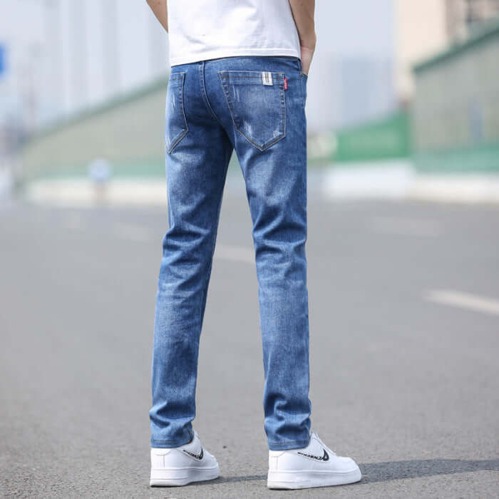 Men's slim straight stretch denim trousers in light blue, perfect for spring and summer, showcased on a model outdoors.