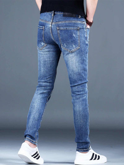 Men's ripped light blue fleece padded jeans showing a slim-fit style from the back, paired with white sneakers.