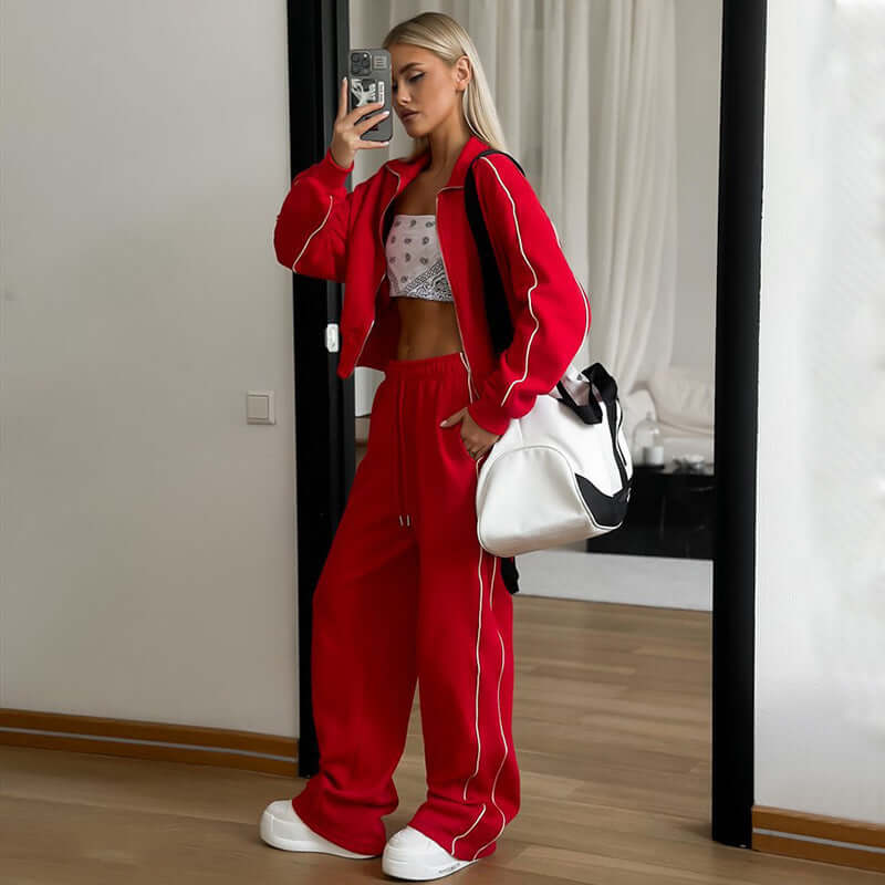 Model wearing red sports lace two-piece set with white accents and oversized bag in modern setting.