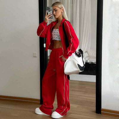 Model wearing red sports lace two-piece set with white accents and oversized bag in modern setting.