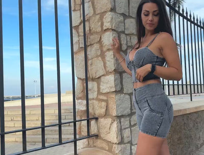 Woman in grey high waist shorts and sleeveless top, showcasing a stylish look outdoors.